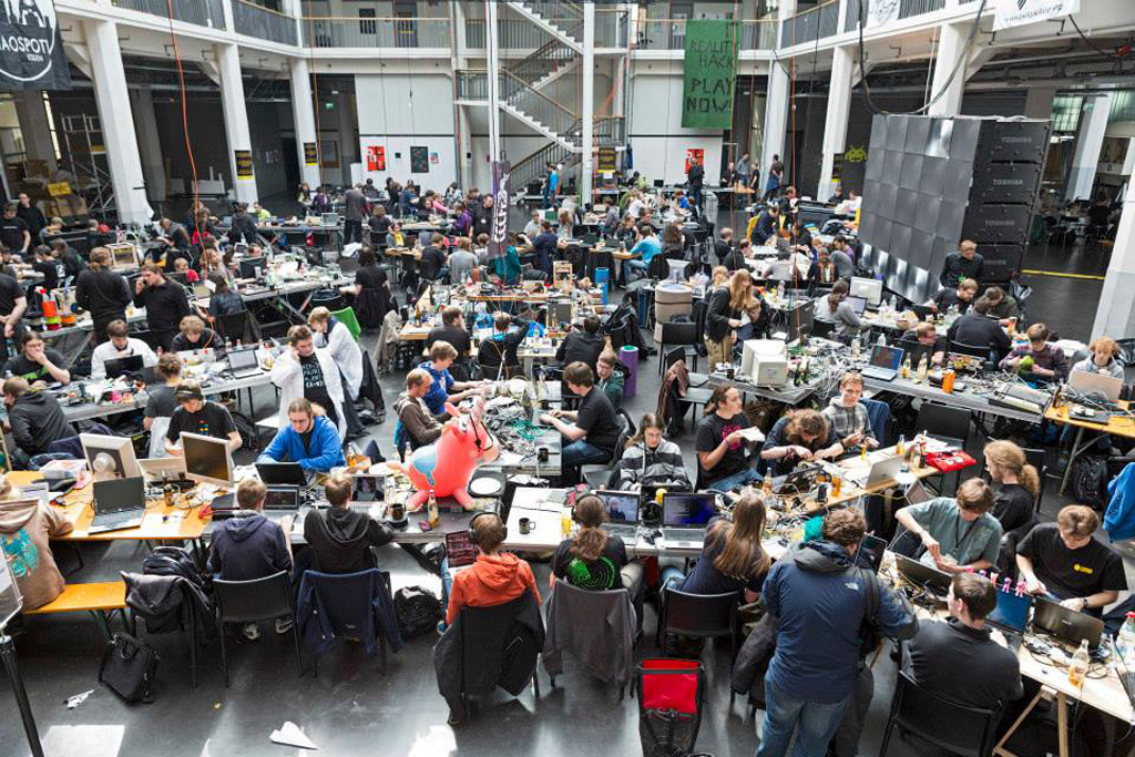 A room full of people who are sitting at desks in front of their computers