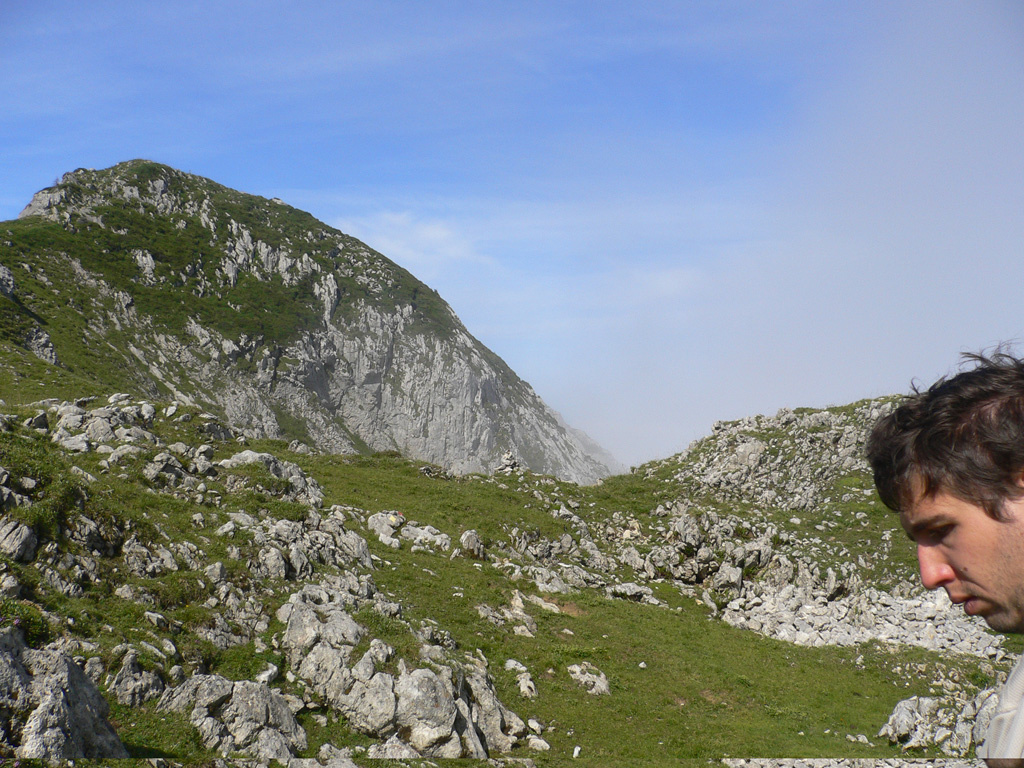 Im Hintergrund Berge, im rechten Bildrand ein Gesicht eines jungen Mannes