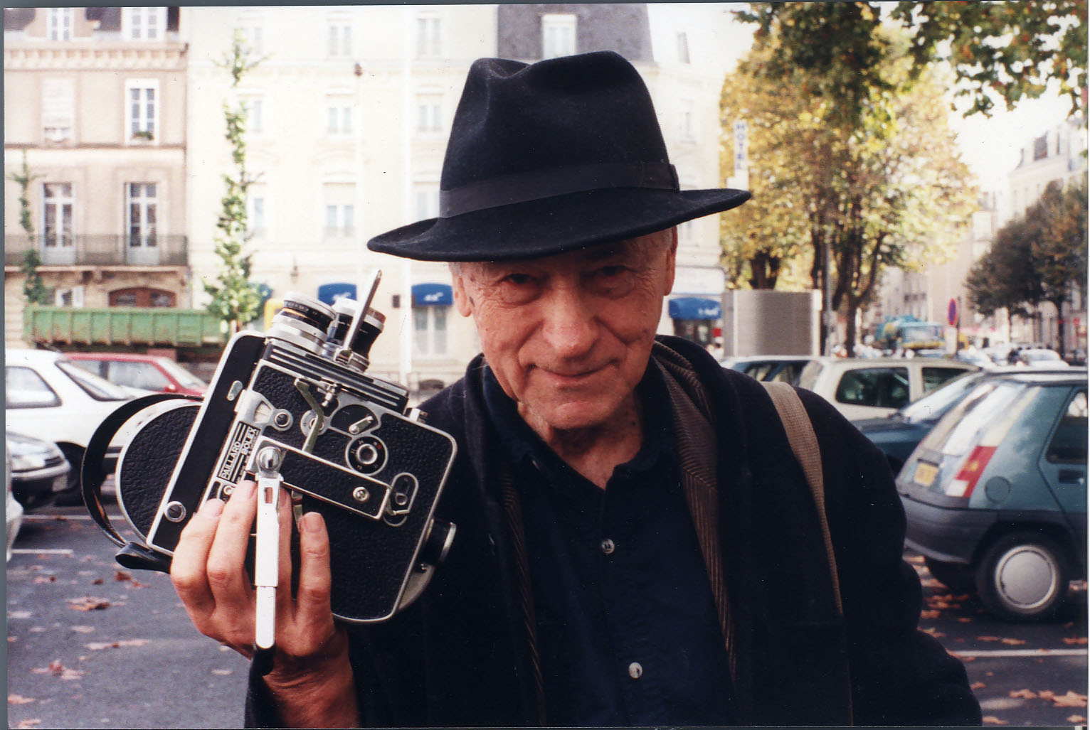 Jonas Mekas mit einem Hut auf dem Kopf und einer Kamera in der Hand