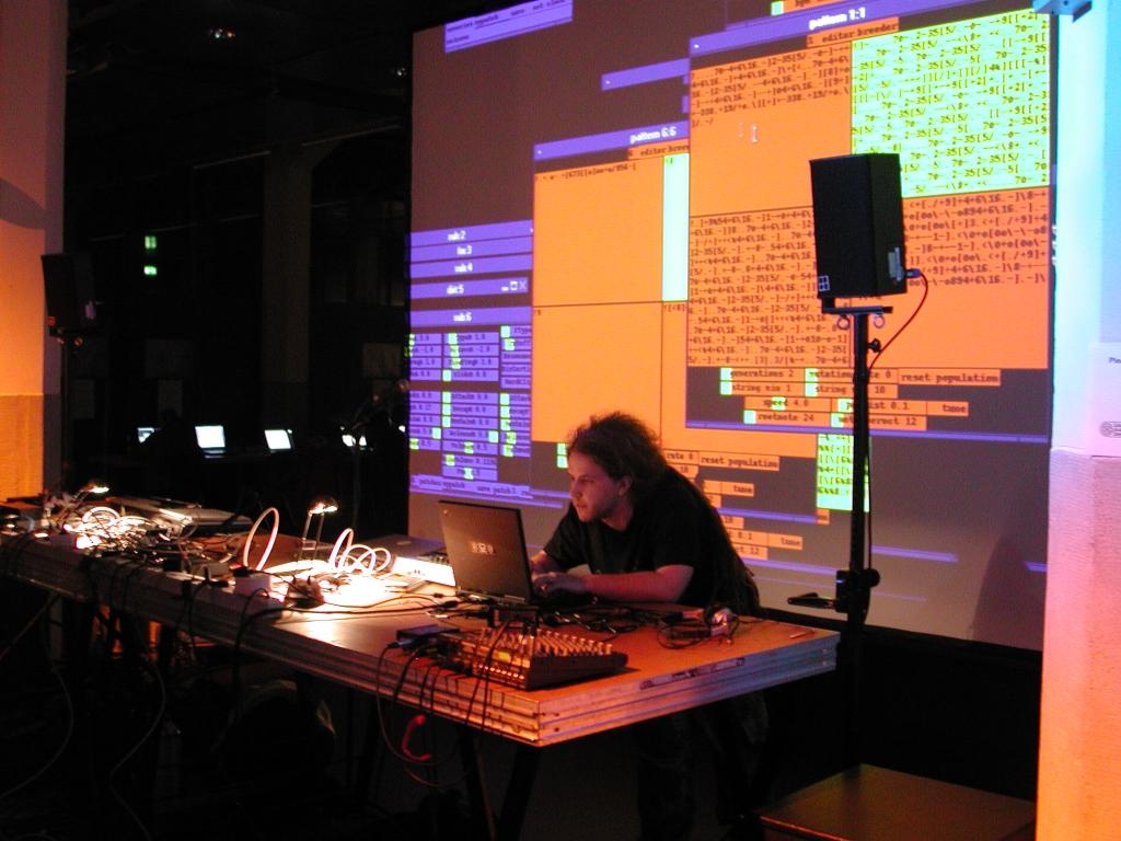 A software developer in his work. The viewer can on a large video screen visually watch the programming.