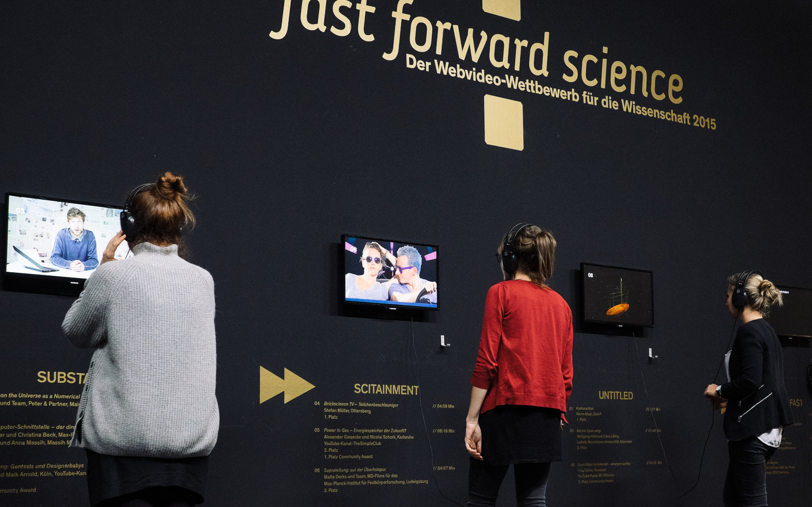 Drei Menschen mit Kopfhörern auf den Ohren schauen verschiedene Videos des »fast forward science 2015« Wettbewerbs an.