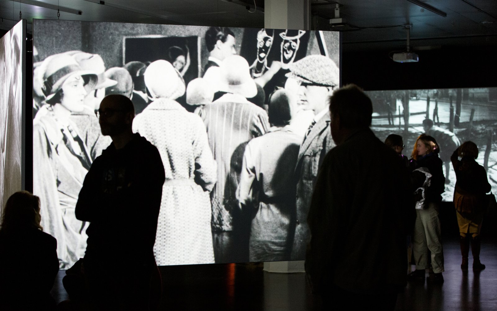 Das Foto zeigt den Ausstellungraum mit einer großen Projektion eines schwarz weiß Filmes.