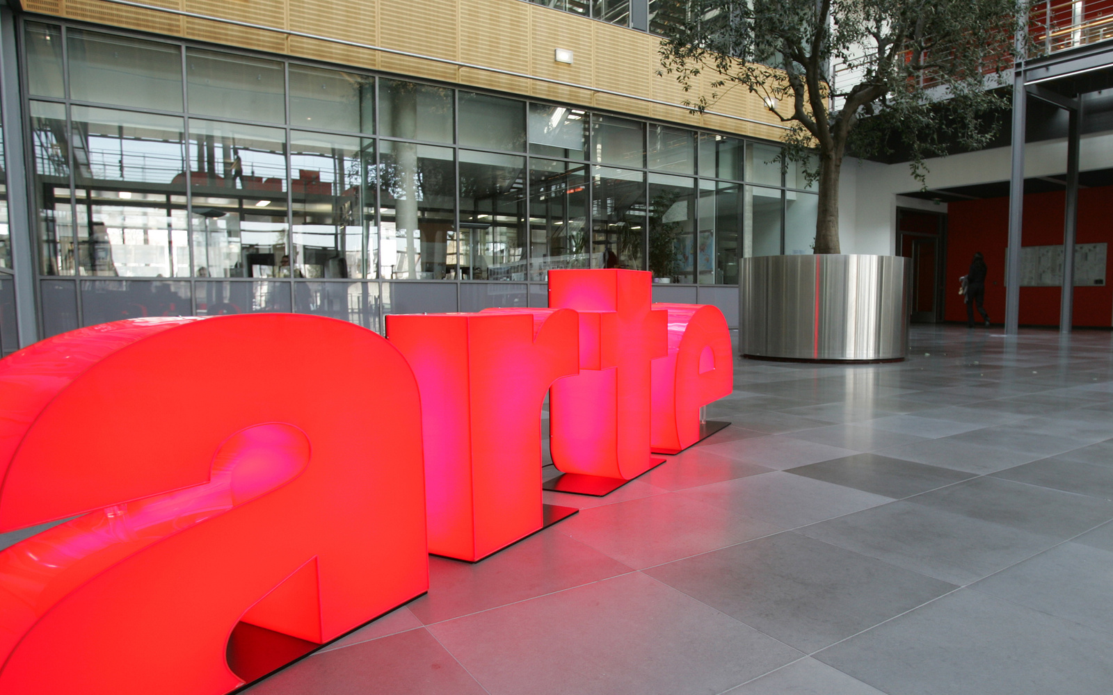 Das arte-Logo steht in leuchtendem Pink in einem gläsernen Atrium.