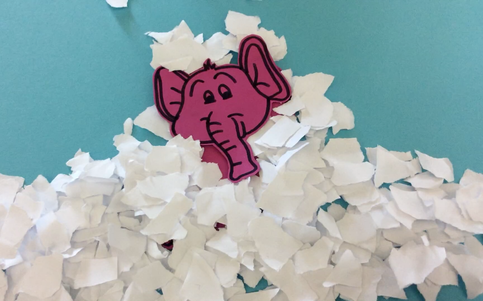 A still out of an stop motion movie with a pink elephant that is covered with shreds of paper, that make him look like he is stuck in snow. 