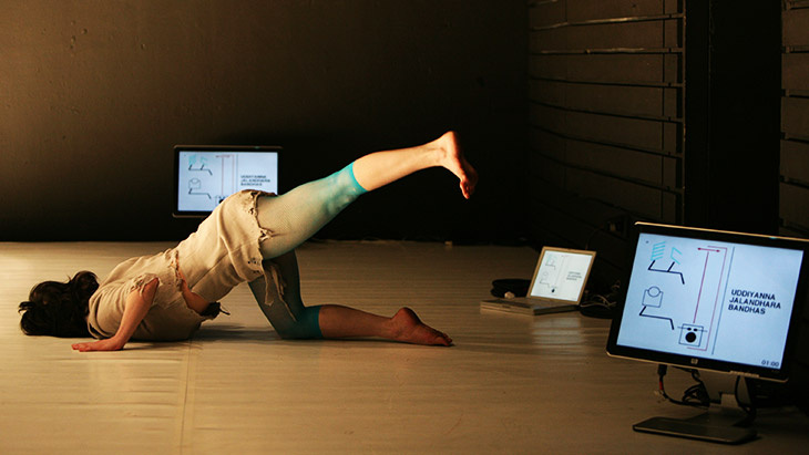 A woman lies with her head towards the floor, while she lifts up her left leg