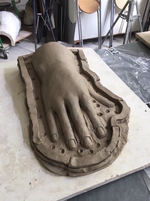 Zu sehen ist eine überdimensionale Hand aus Ton