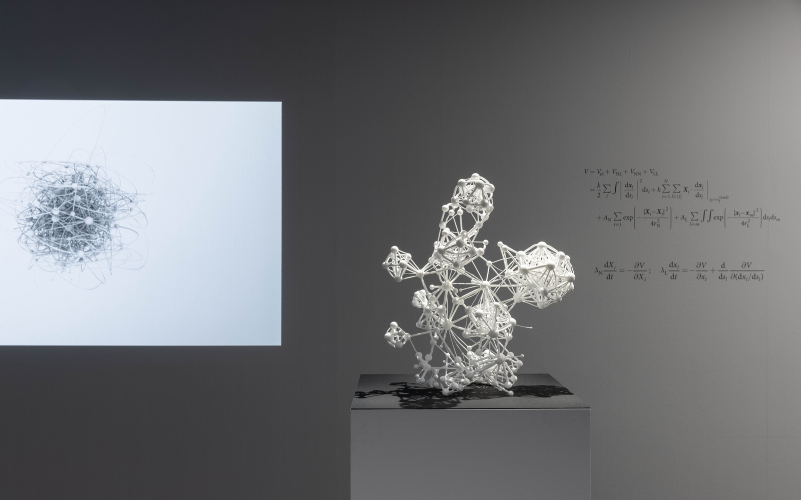 Three-dimensional sculpture of the "Flavor Network" in white. On the wall in the background is a mathematical algorithm formula.