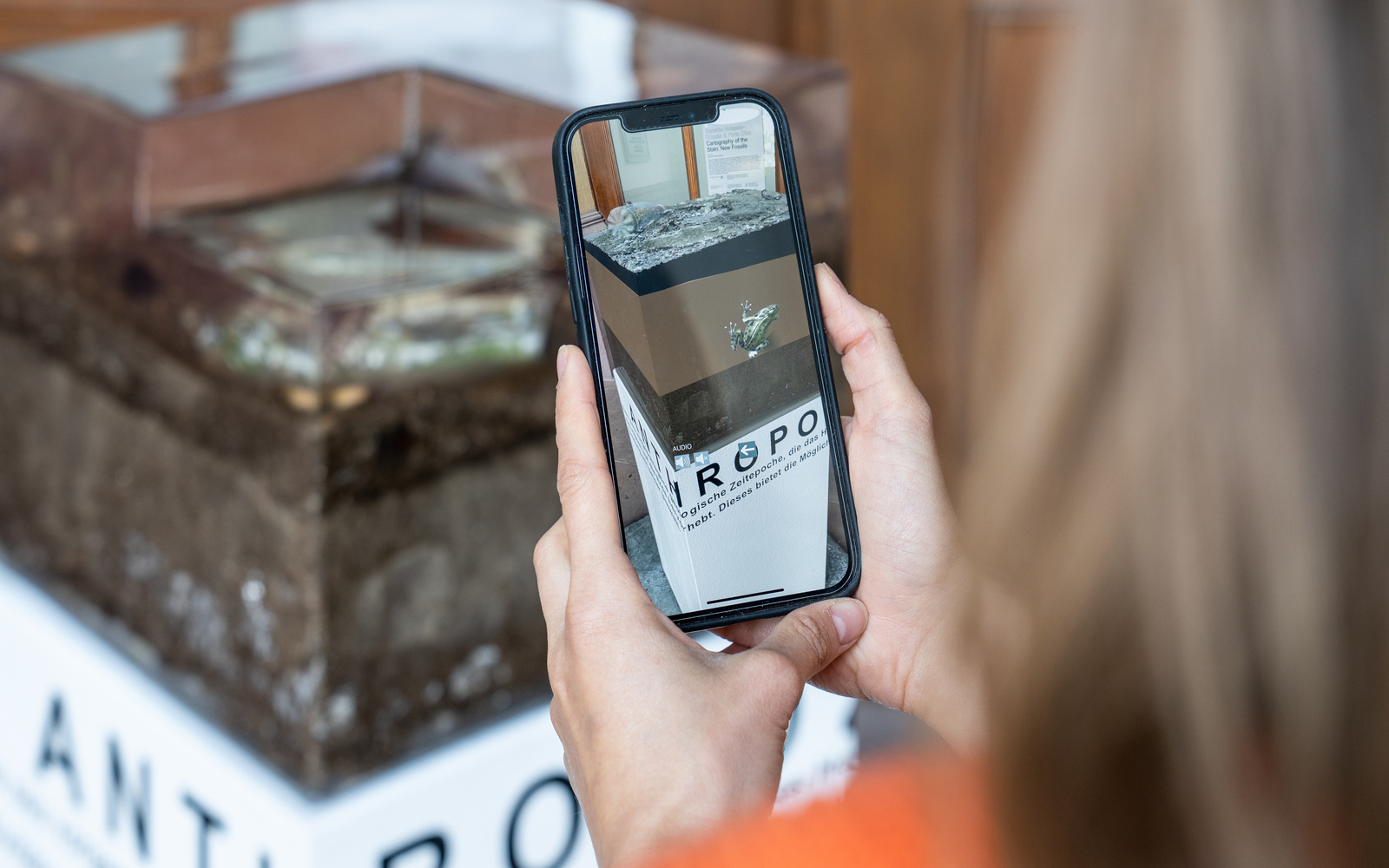 Zu sehen ist eine Person, welche die Installation mittels AR über das Smartphone betrachtet