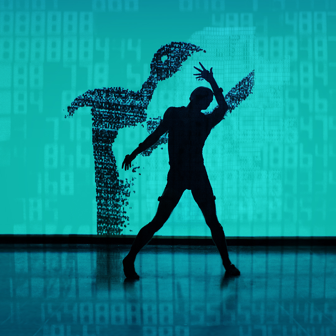 The photo shows a stage with turquoise background and black floor, on which the silhouette of a dancing man can be seen, whose shadow is depicted on the back wall.