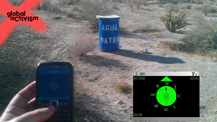 A Hand holding a mobile phone and a barrel in the field