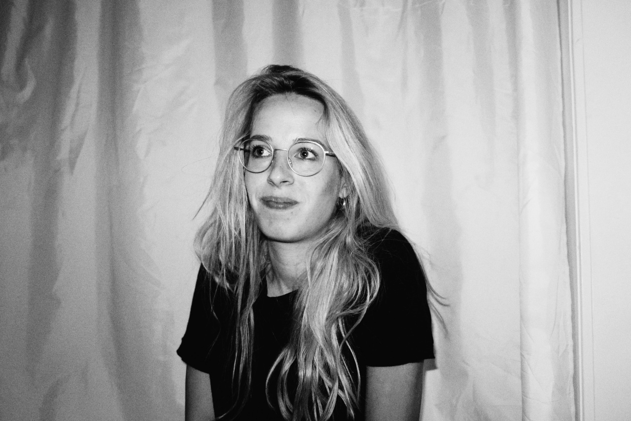 A young woman with long hair and glasses looks into the camera, she appears cheerful. It is a portrait photo.