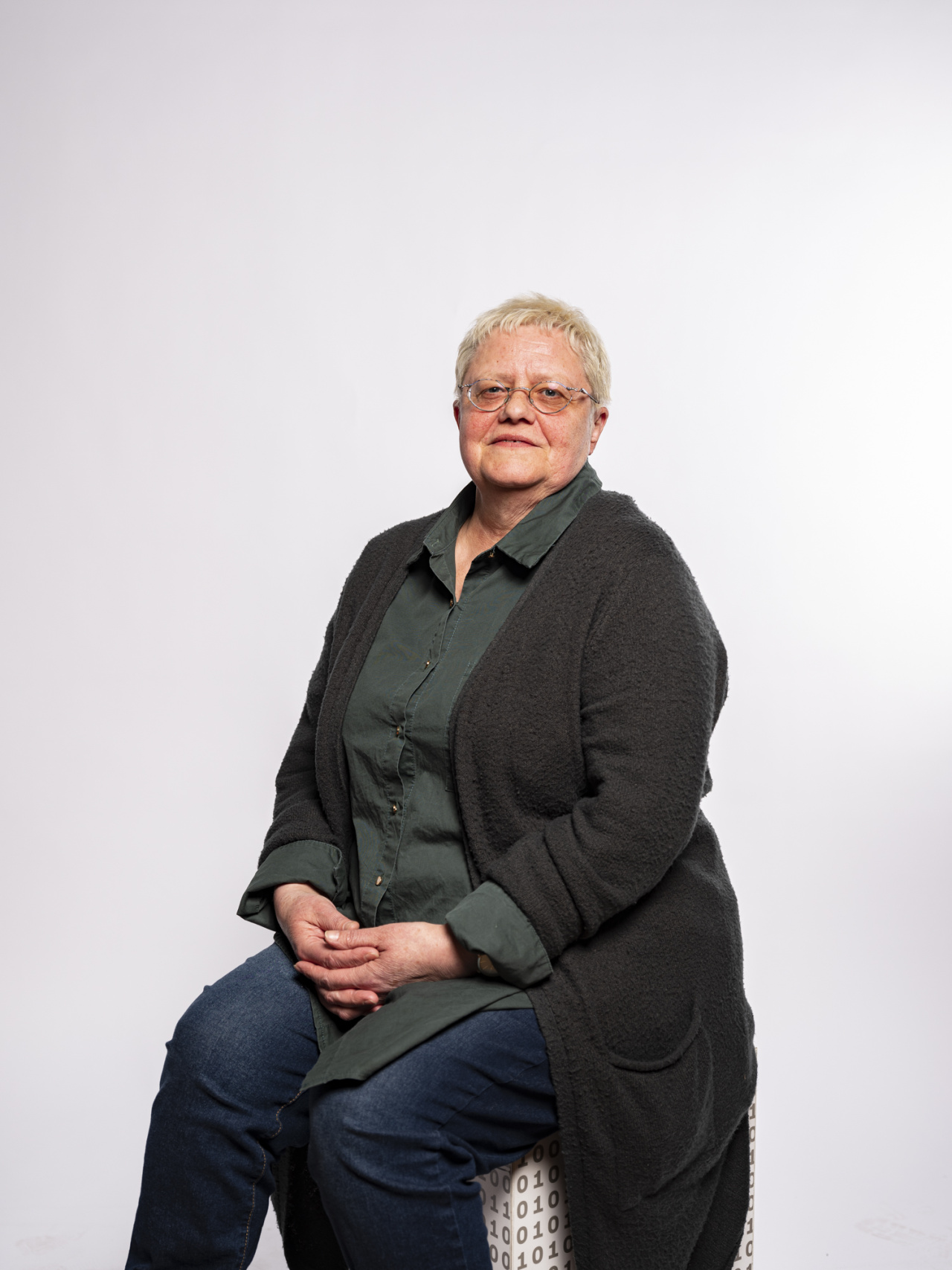 sitzende Frau mit kurzen grauen Haaren und Brille
