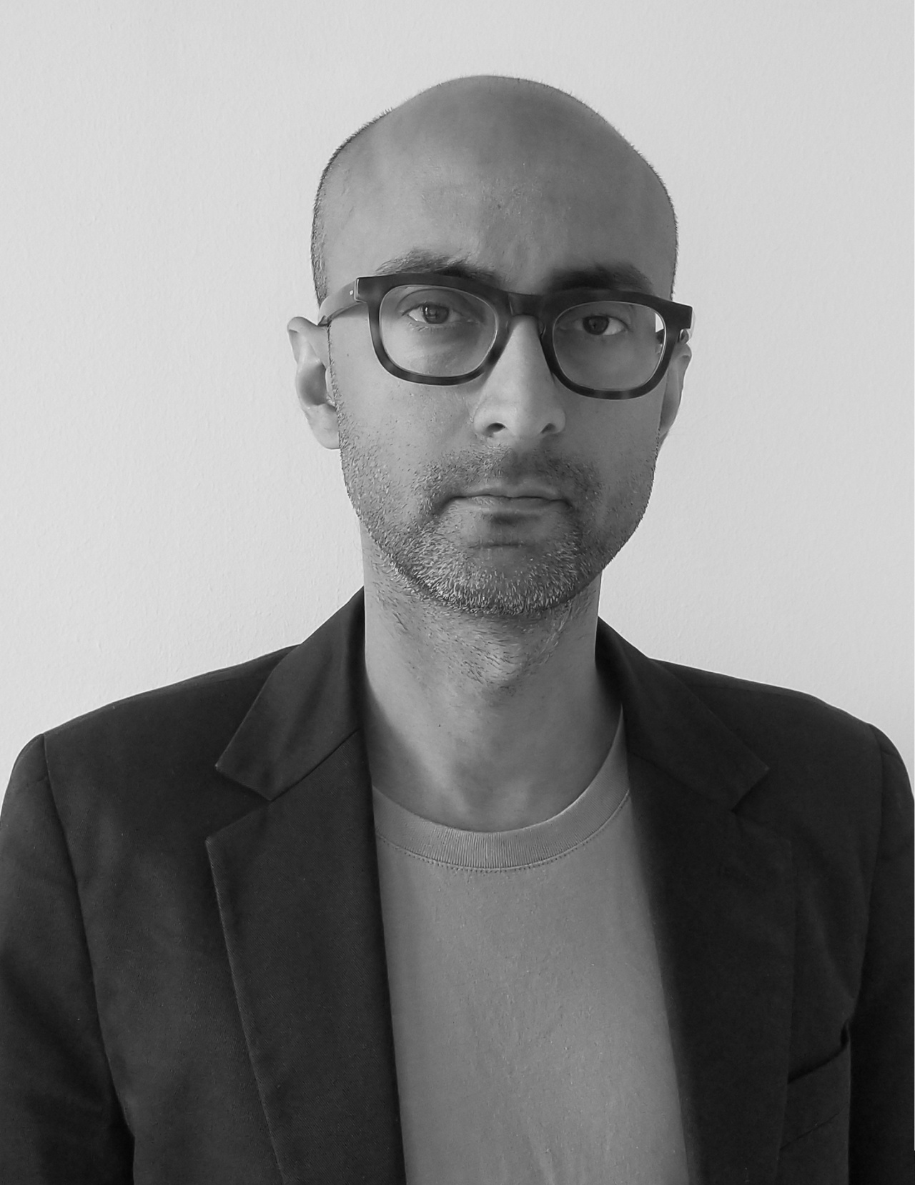 Schwarz-weiß Foto eines Manns mit Brille im Sakko
