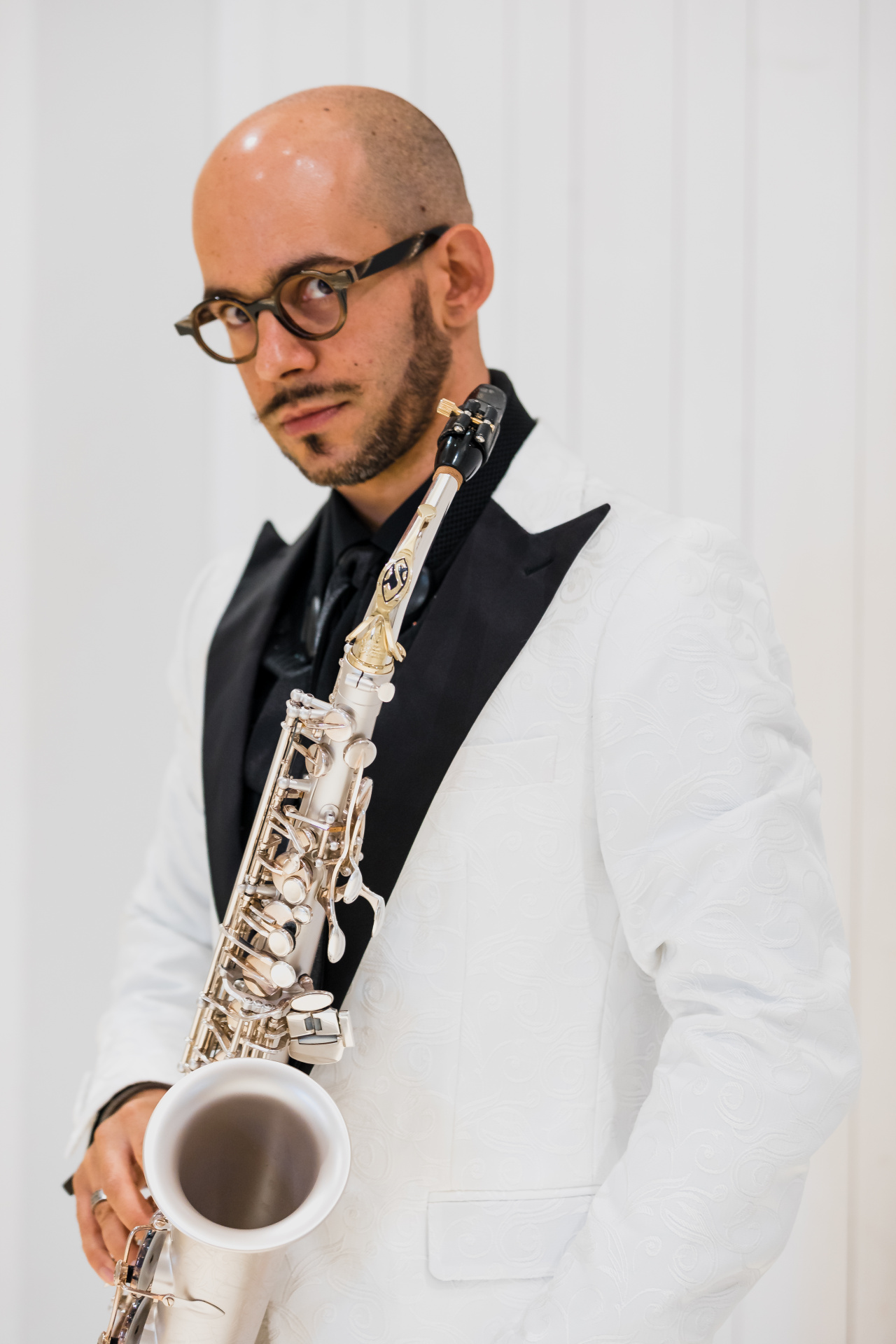 Sie sehen eine Person in einem weißen Anzug mit einem Musikinstrument. 