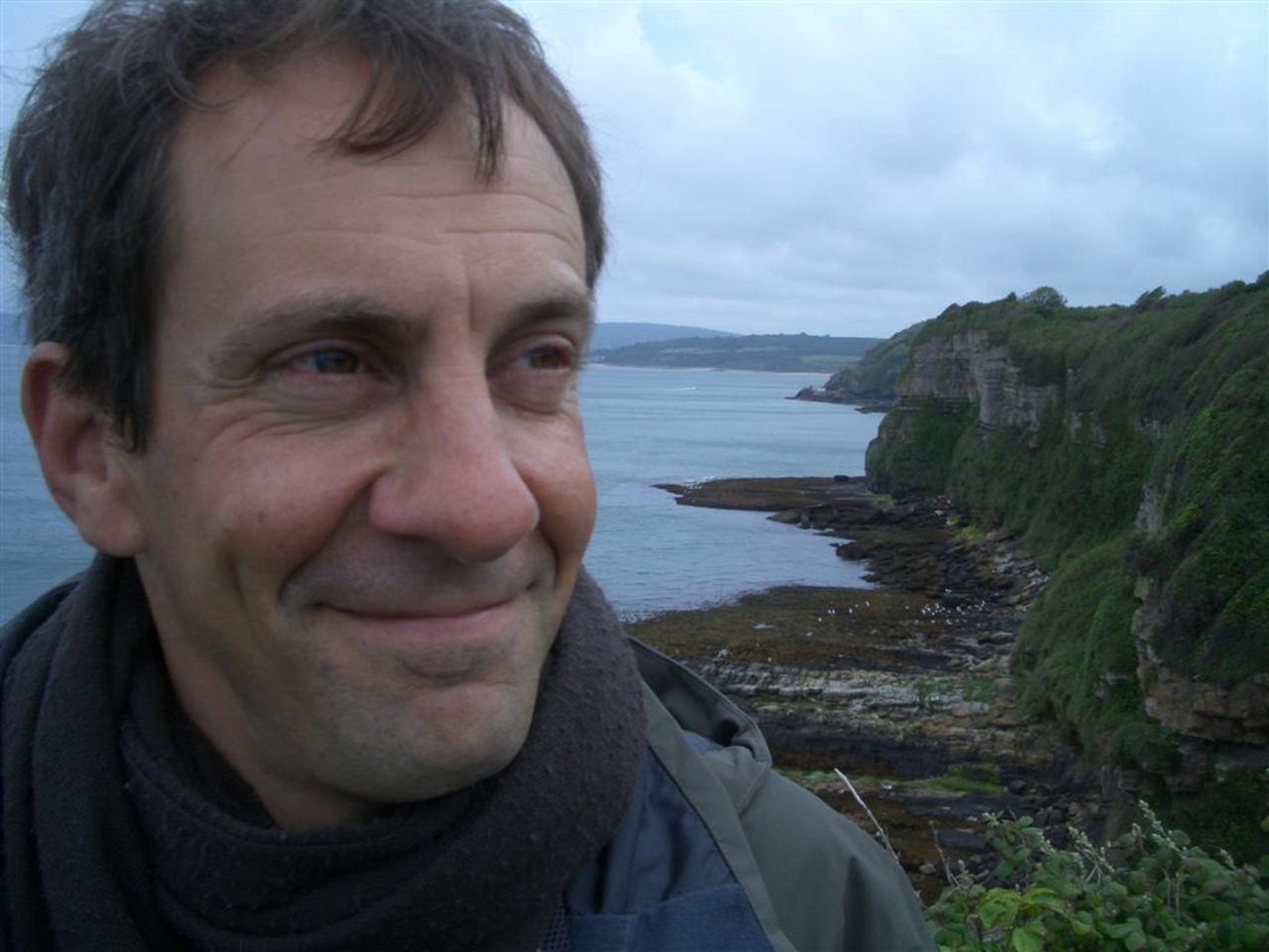 Portrait von David Link. Im Vordergrund der Künstler, im Hintergrund eine Meeresküste
