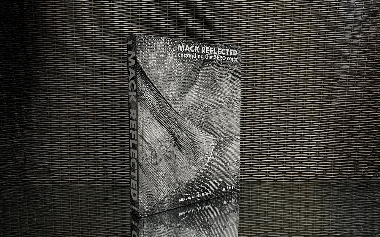 The image shows a book, standing on a reflective surface that reveals its mirror image.