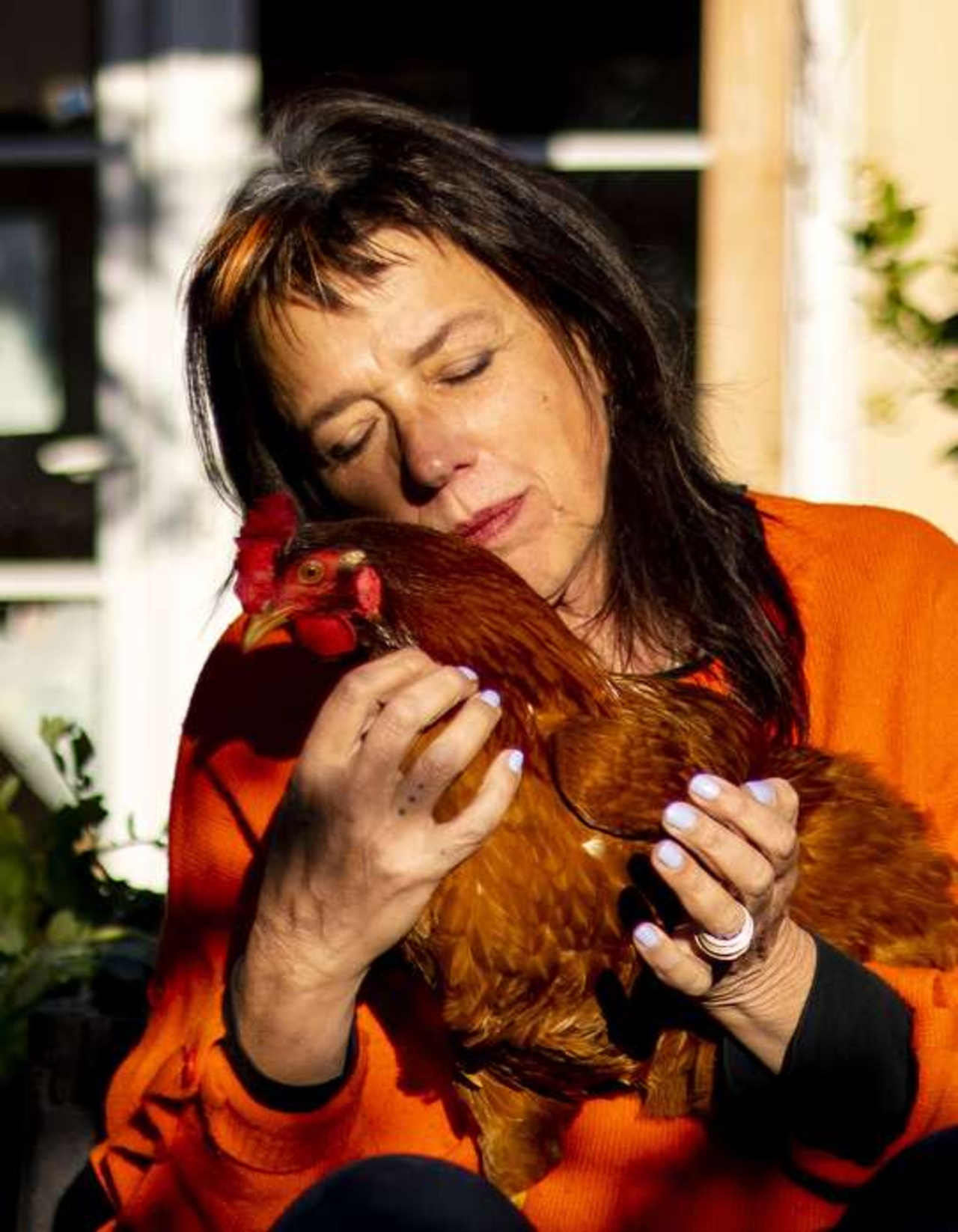 Photo of a person in a green top with a chicken on his arm.
