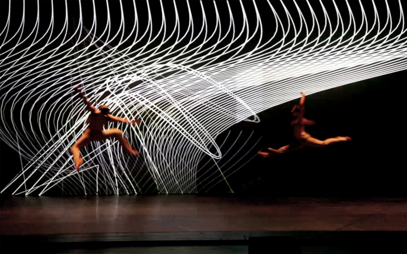 A stage. Two dancers move through the air. In the background spirally white structure.