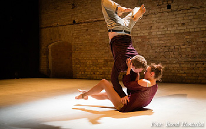 A dancing couple on stage. While this makes on her hips a handstand, she tries to kiss him.