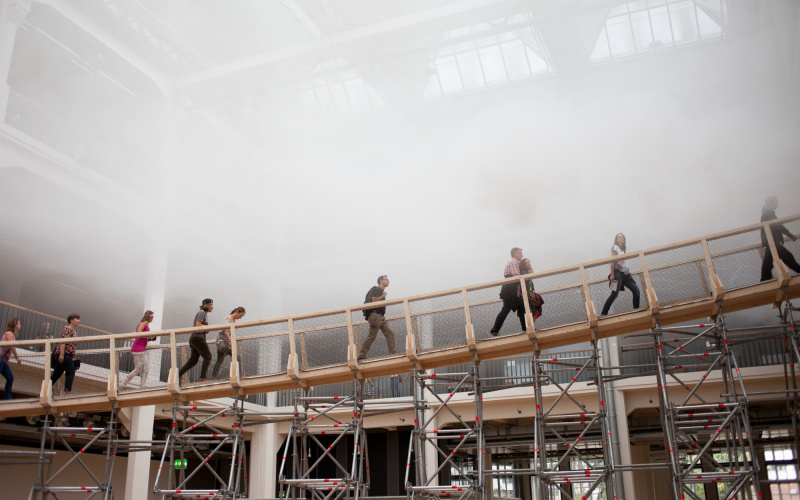 Menschen laufen über eine Rampe durch Nebel
