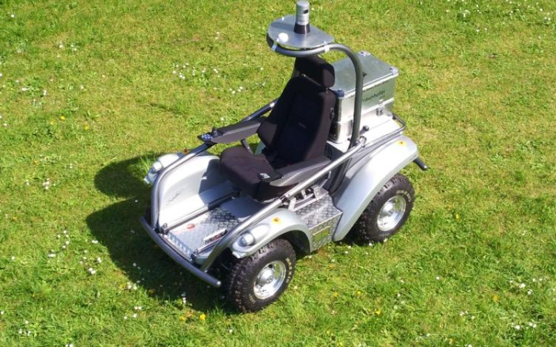 Graues Fahrzeug mit schwarzem Sitz auf einer grünen Wiese