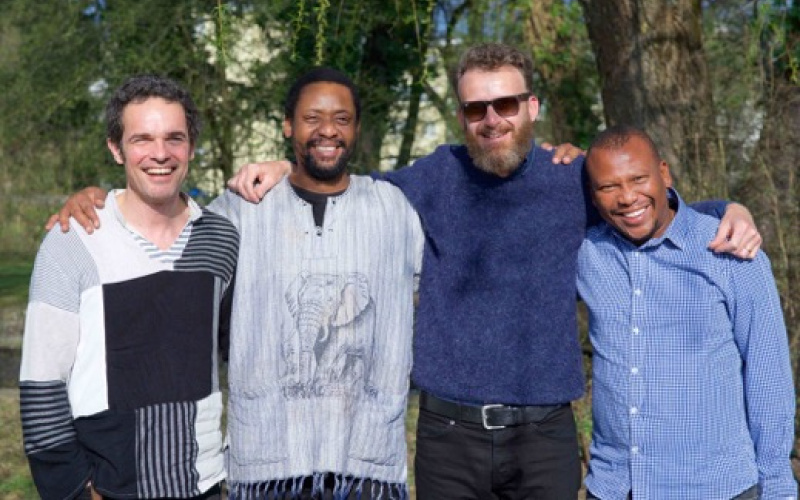 Das Bild zeigt die vier strahlenden Mitglieder von Bänz Oester & The Rainmakers