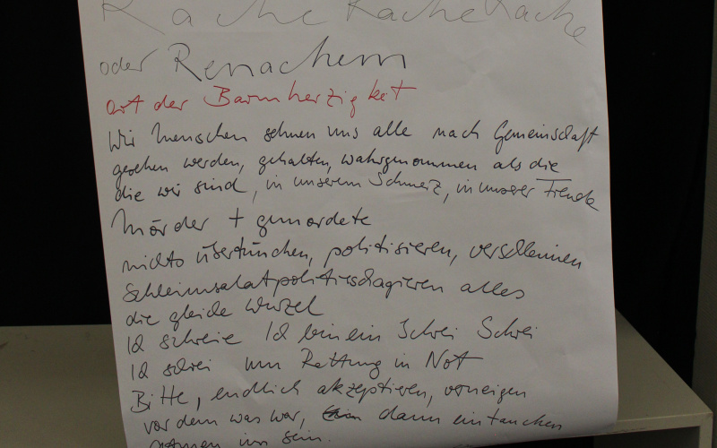 Jemand hält ein riesiges Blatt vor sich, sodass man nur noch die beiden Hände sieht. Auf dem Blatt stehen Ergebnisse von einem Workshop geschrieben.