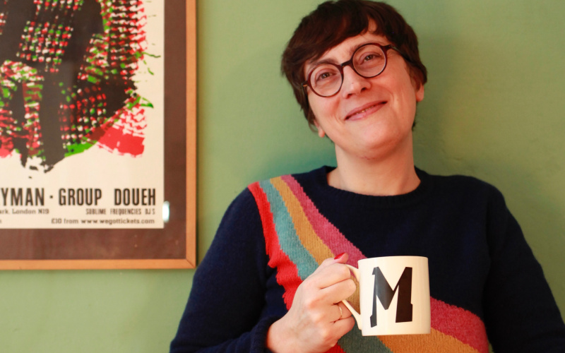 The pictures shows Marie Pierre smilying into the camera and holding a cup with the letter M on it.