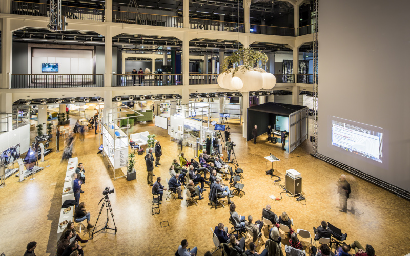 Das Bild zeigt das mit Menschen gefüllte OpenHub der Ausstellung »Open Codes«