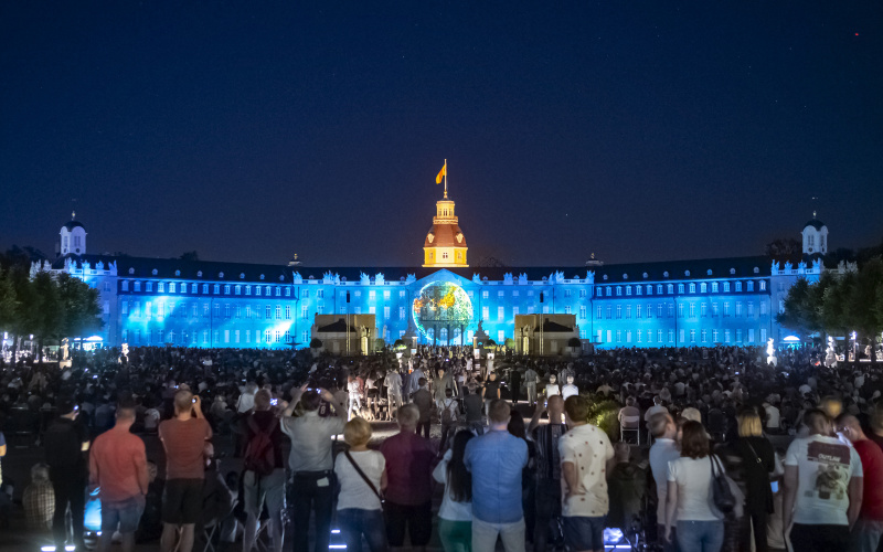 Im MIttelpunkt der Schlossfassade unterhalb des Schlossturmes leuchtet die Weltkugel in einem blauen Meer auf.