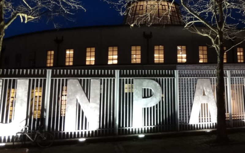 Night scene: On a fence, the letters "UNPAINTED" are attached.
