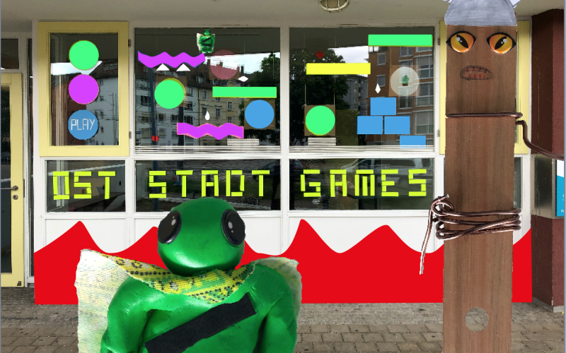 Außenansicht eines Fensters mit Basteleien und der Aufschrift »Oststadt Games«, im Vordergrund weitere Bastelarbeiten
