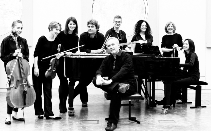 Zu sehen ist das »Ensemble Experimental« bestehend aus acht Personen. Eine Person sitzt vor einem Klavier und der Rest steht dahinter. Das Bild ist schwarz-weiß.