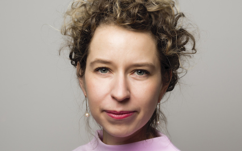 A woman with curly blonde hair in a pink sweater