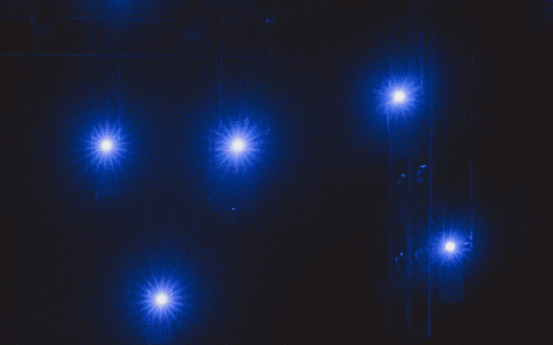 Zu sehen sind fünf blaue Lichter in einem dunklen Raum. 
