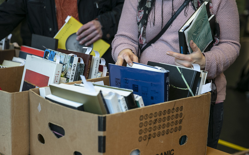 Bild einer Bücherkiste mit Händen, die danach greifen.