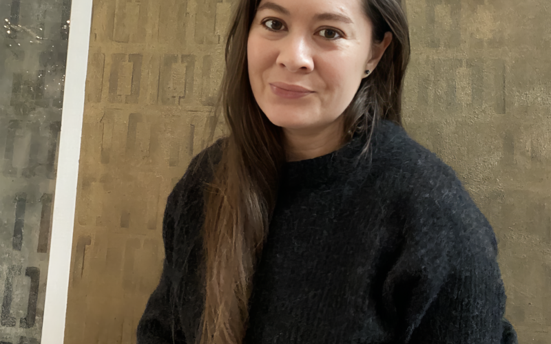 Portrait photograph of a person in front of a wall.