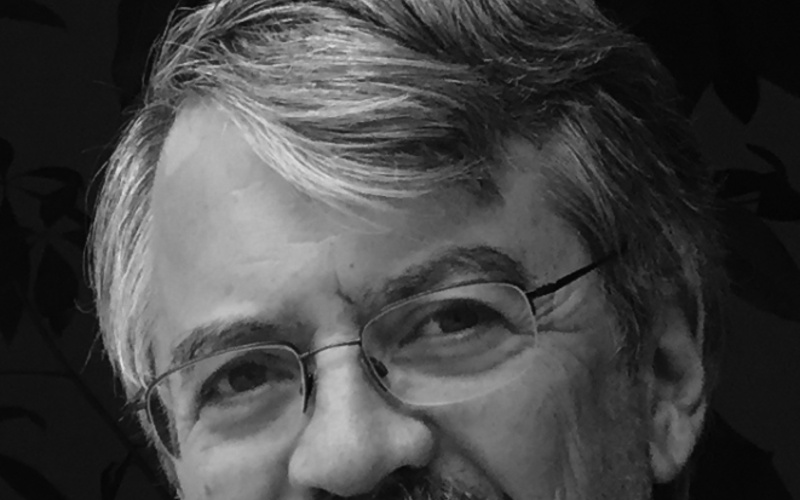 A portrait photo of Lew Tucker is shown. 