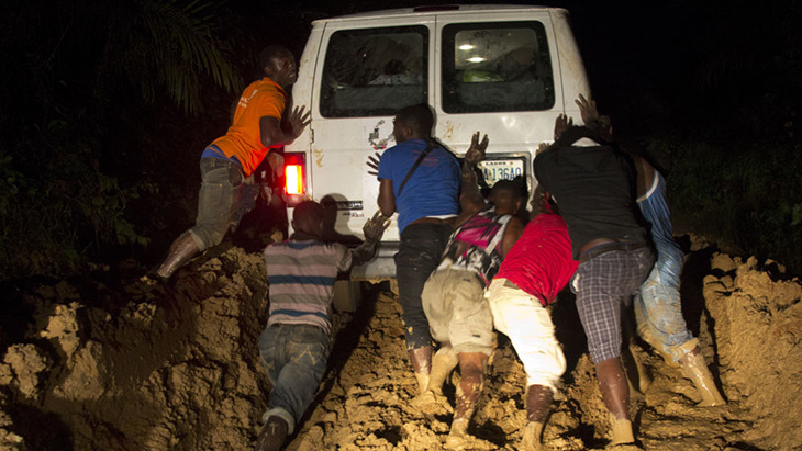 Several men are pushing a white minivan
