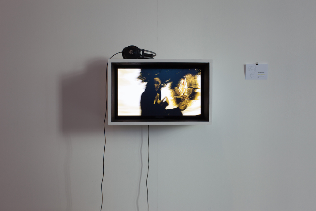  An der Wand hängt ein Monitor, auf dem ein Film läuft