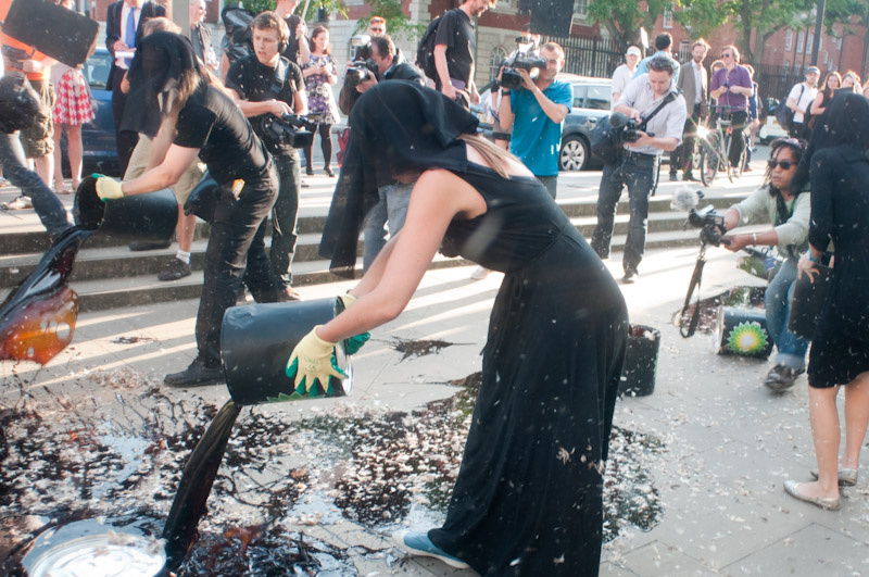 Two people are spilling oil on the street