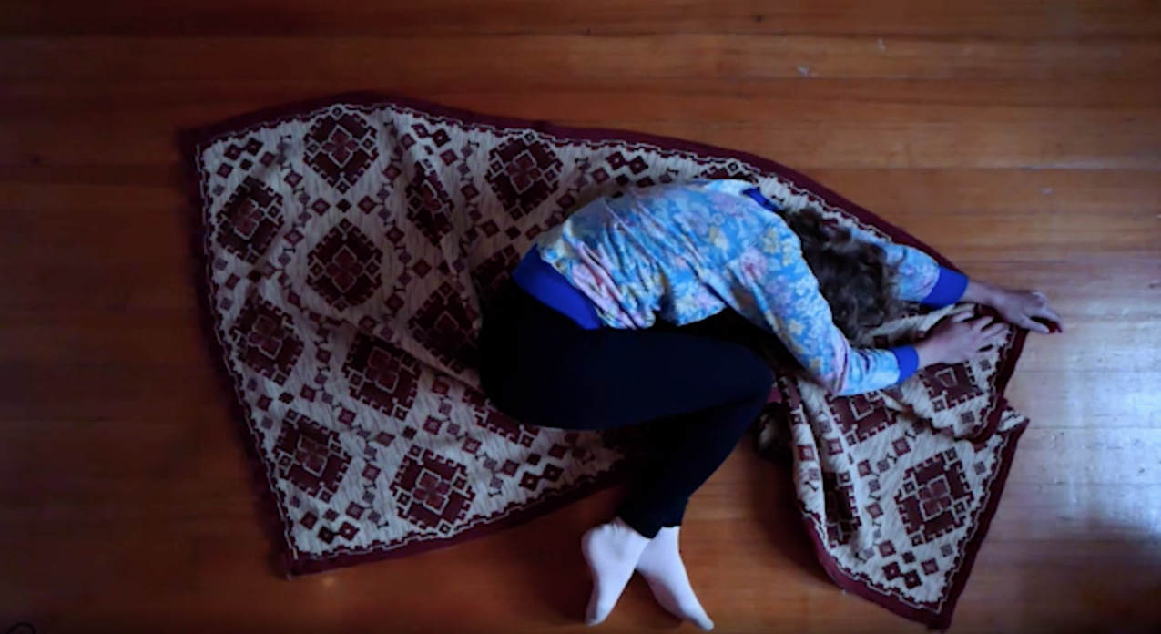 The picture shows a person lying on a carpet and writhing on it.