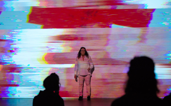 Noa Frenkel is standing in front of a background in different colours. The texture of the background corresponds to the spatula technique