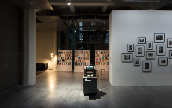 Blick in die Ausstellung »Beat Generation«: Zu sehen sind im Hintergrund einige Bücher, im Zentrum eine alte Druckmaschine und am rechten Rand mehrere Schwarz-Weiß-Fotografien