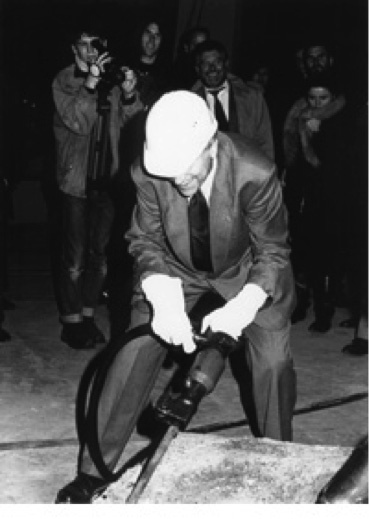 Ein Mann mit Bauarbeiterhelm und Druckluft-Meißel in den Händen.
