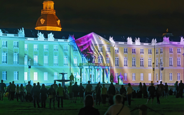 Das Karlsruher Schloss ist in türkis und rosa Licht getaucht
