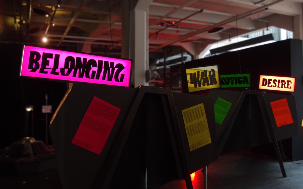 Blick in die Ausstellung: Leuchttafeln mit den Worten: Belonging, War, Desire. 