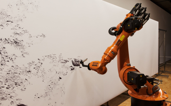 Ein Industrieroboter zeichnet ein mit einem Stift auf ein Großformat