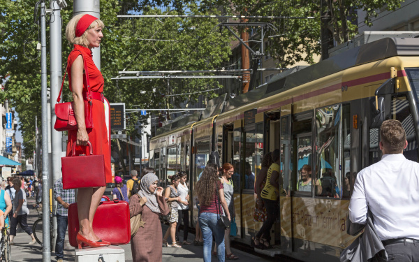 A woman in red is standing on a power box in the middle of the pedestrian zone