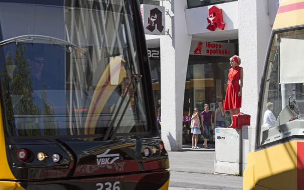 A woman in red is standing on a power box in the middle of the pedestrian zone